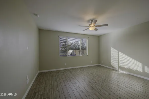 an empty room with wooden floor chandelier fan and windows