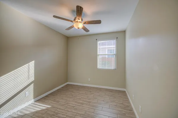 an empty room with wooden floor fan and windows