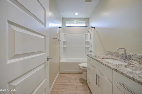 a bathroom with a granite countertop sink mirror vanity and toilet