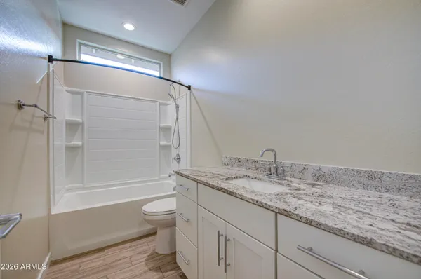 a bathroom with a granite countertop sink a toilet and shower