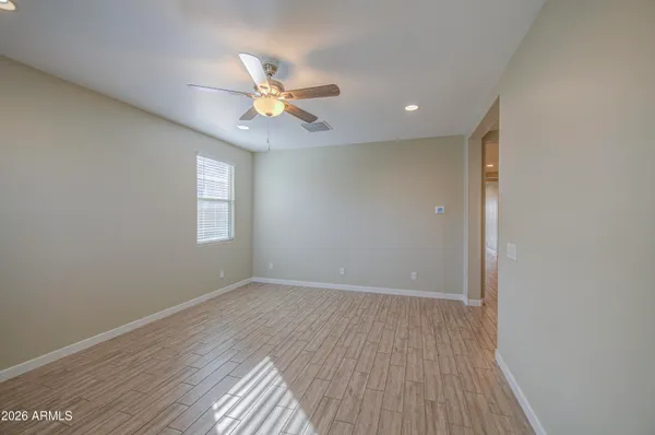 a view of empty room with wooden floor and fan
