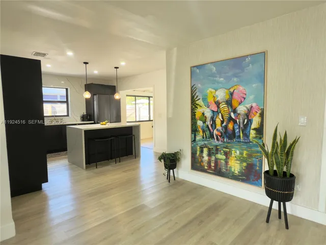 a living room with stainless steel appliances furniture and a kitchen view