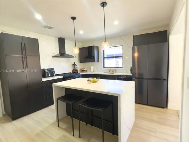 a kitchen with kitchen island a sink stove and refrigerator