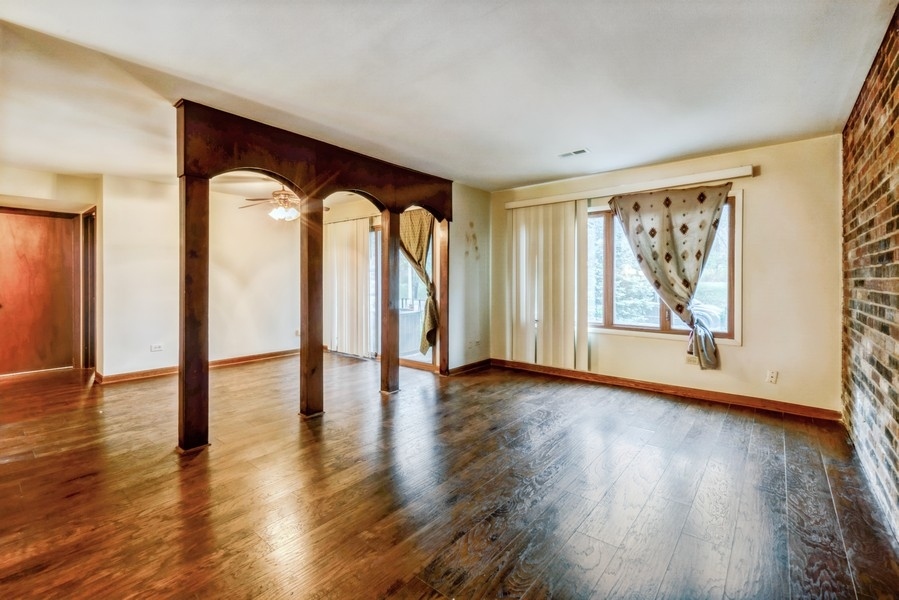6027 103rd Street, Unit 1B Chicago Ridge, IL 60415 - Photo 3 of 9 a view of an empty room with wooden floor and a window