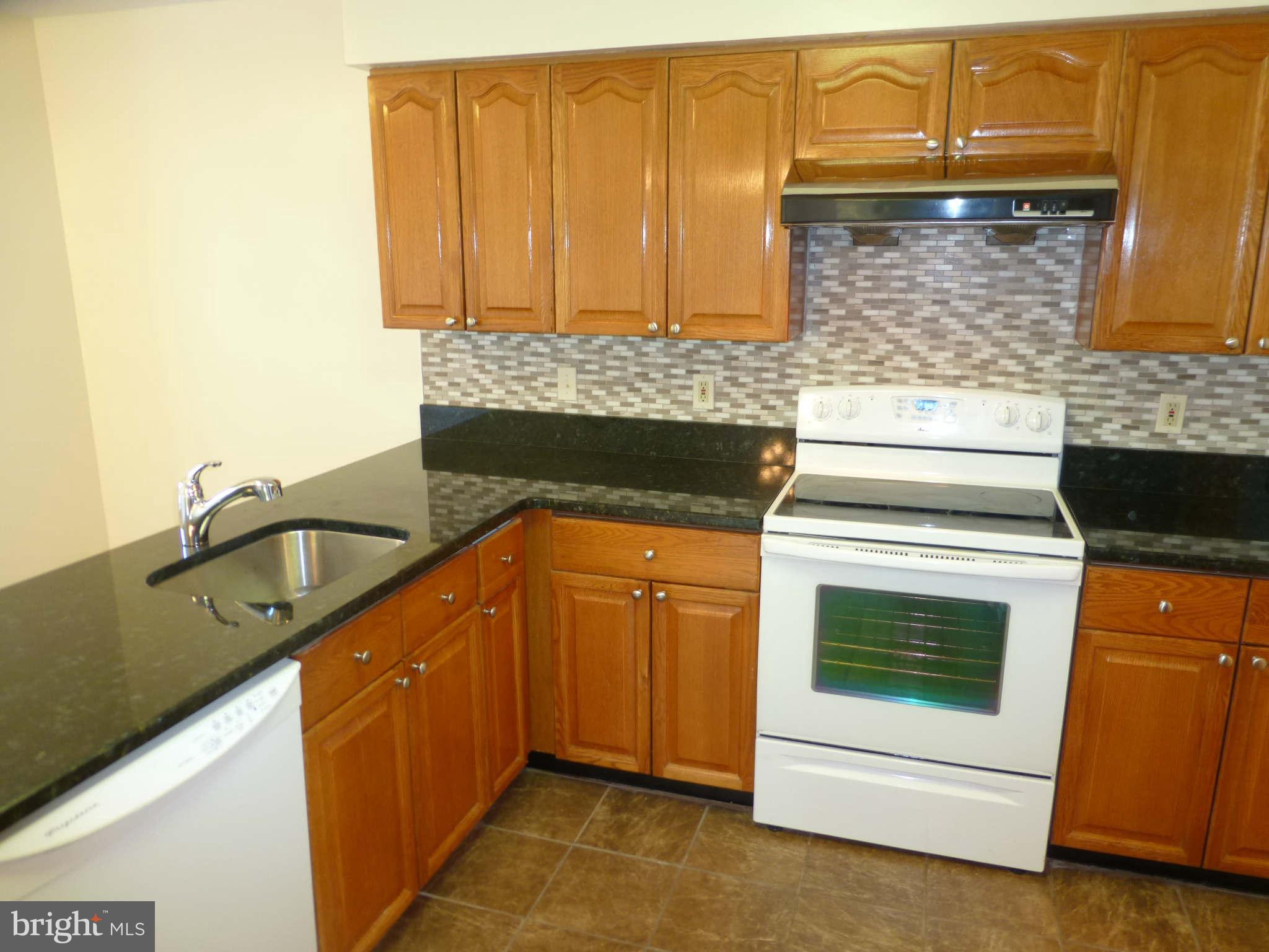 7311 Treetop Hill Lane Springfield, VA 22152 - Photo 7 of 26 a kitchen with granite countertop a sink stove and cabinets