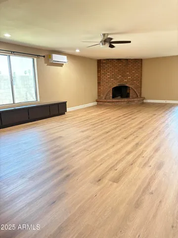 an empty room with wooden floor a fireplace and windows