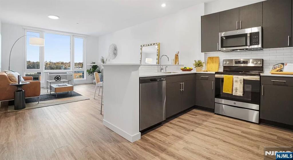 150 Main Street, Unit 405 Hackensack, NJ 07601 - Photo 7 of 12 a kitchen with stainless steel appliances granite countertop a refrigerator a stove top oven a sink dishwasher and wooden cabinets with wooden floor