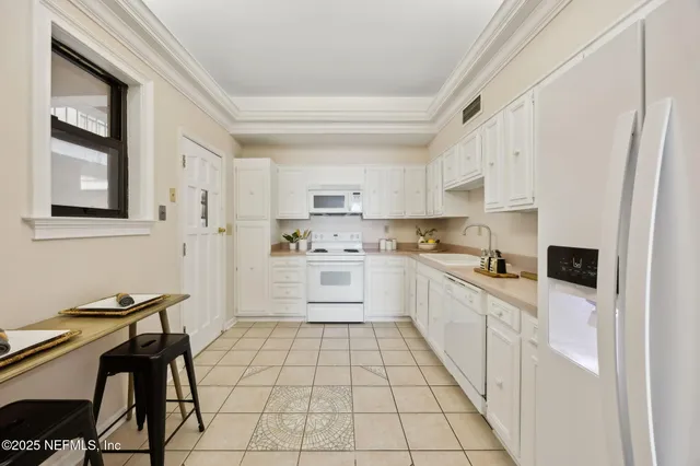 a kitchen with white cabinets white stainless steel appliances and sink