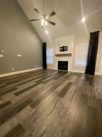 an empty room with fireplace fan and windows