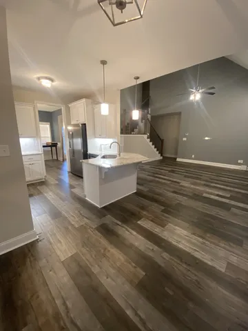 a living room with couches and kitchen view with wooden floor