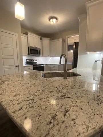 a kitchen with kitchen island granite countertop a stove a sink and a microwave