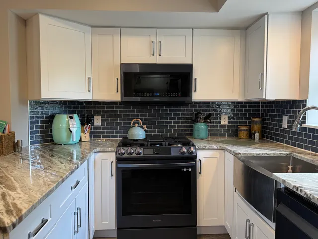 a kitchen with granite countertop a sink a stove and cabinets