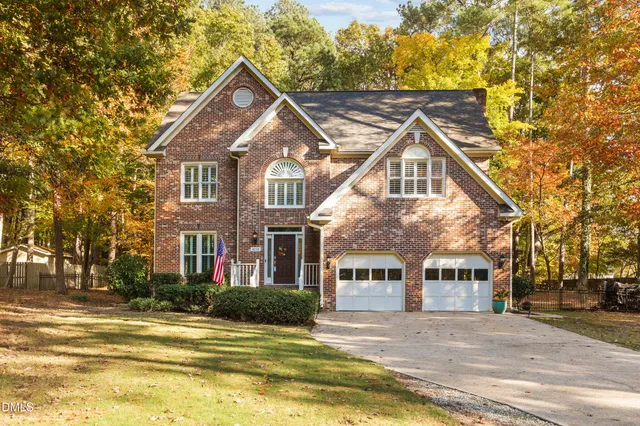a view of a house next to a big yard and large trees