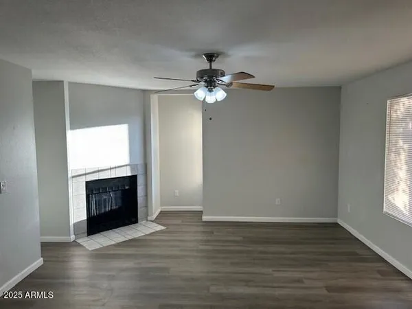 an empty room with wooden floor chandelier fan and windows