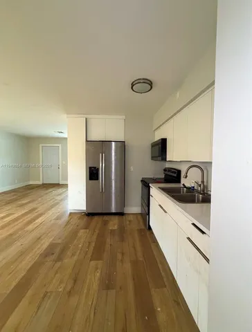 a large kitchen with cabinets wooden floor and stainless steel appliances