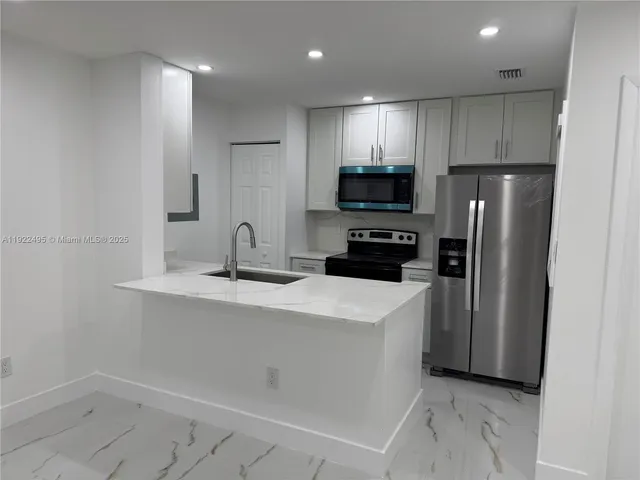 a kitchen with a sink a refrigerator and cabinets