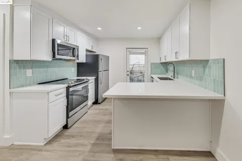 a kitchen with stainless steel appliances a sink a stove a microwave a sink a refrigerator and cabinets