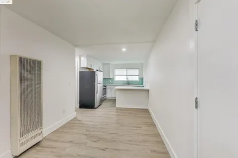 a view of a kitchen with refrigerator and wooden floor