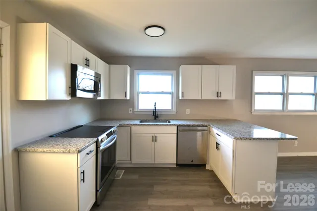 a kitchen with stainless steel appliances granite countertop a stove a sink and a microwave
