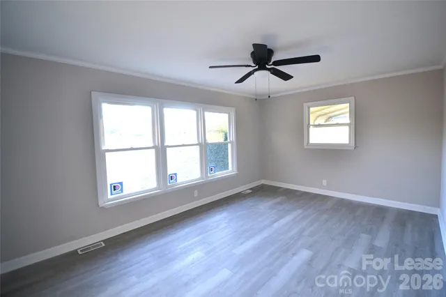 a view of an empty room with wooden floor and window
