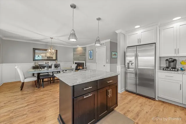 a kitchen with stainless steel appliances granite countertop a kitchen island a stove a refrigerator a sink a dining table and chairs