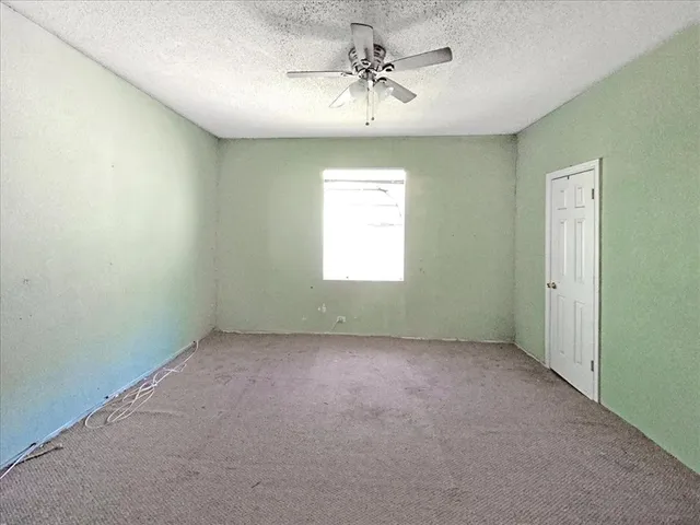 an empty room with a window and a fan