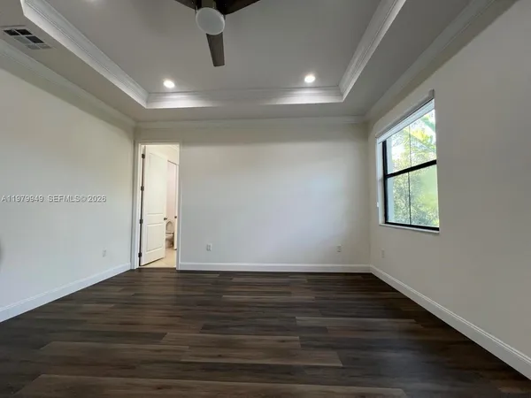 a view of an empty room with wooden floor and windows