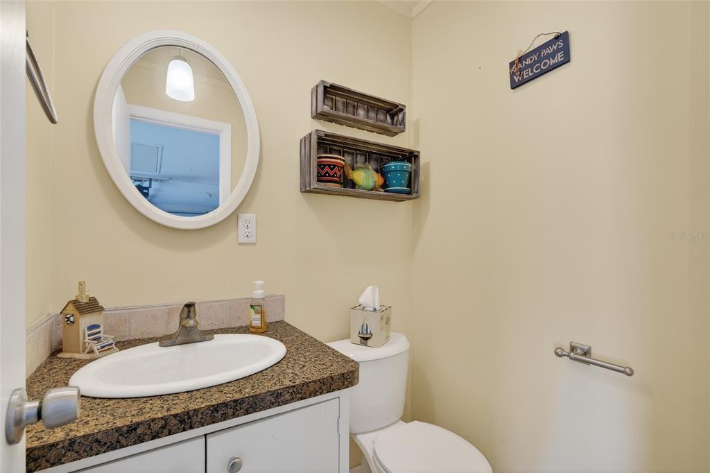 9238 140th Lane Seminole, FL 33776 - Photo 26 of 36 a bathroom with a granite countertop toilet a sink and a mirror
