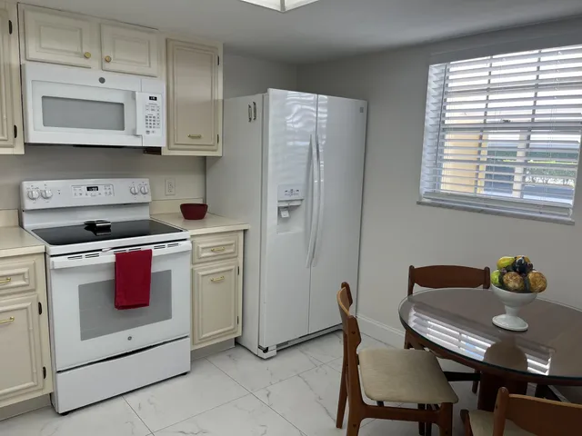 a kitchen with stainless steel appliances granite countertop a stove a microwave a dining table and chairs