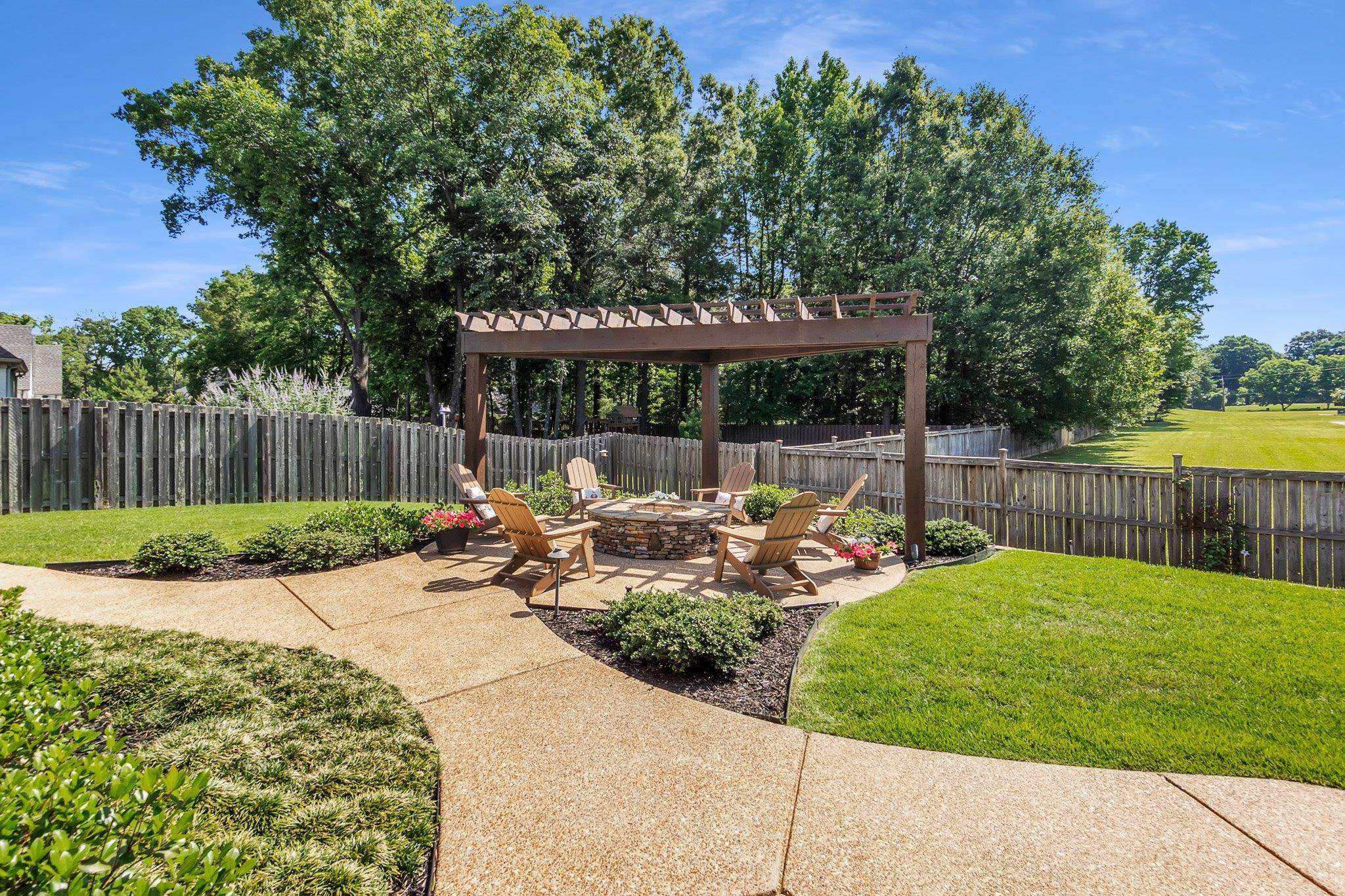 3246 North Hartwell Ridge Drive Collierville, TN 38017 - Photo 40 of 40 Expansive backyard featuring a stone fire pit area with a pergola, a wooden fence, a concrete patio, and lush green lawn
