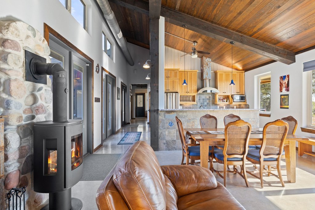 1292 Upper Turtle Creek Road Kerrville, TX 78028 - Photo 10 of 40 Dining area featuring a wood stove, ceiling fan, a wooden ceiling with exposed beams, and high vaulted ceiling