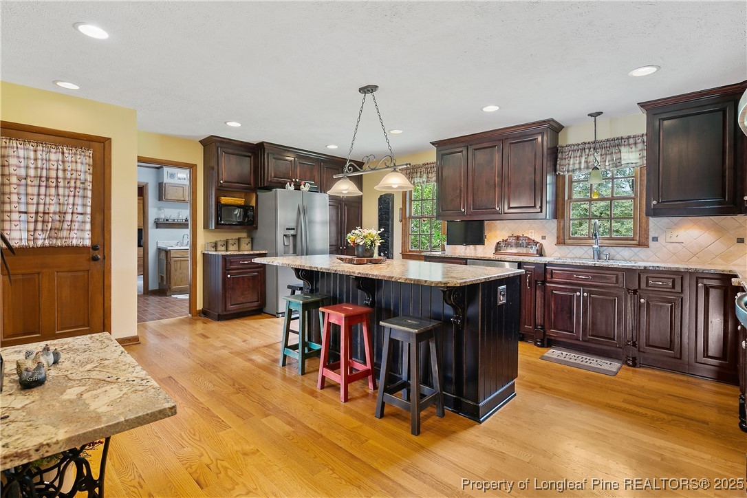 5017 Goldsboro Road Wade, NC 28395 - Photo 9 of 50 a kitchen with stainless steel appliances kitchen island granite countertop a table chairs and a refrigerator