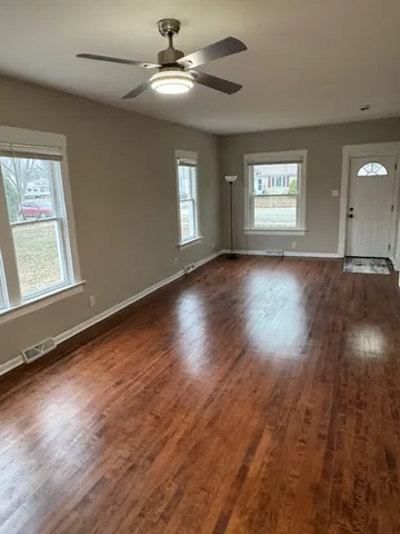 a view of an empty room with wooden floor and a window