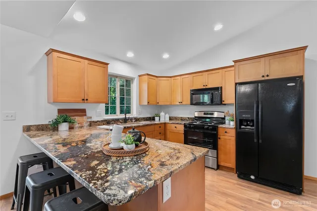 a kitchen with stainless steel appliances granite countertop a stove refrigerator sink and cabinets