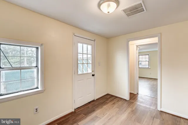 an empty room with wooden floor and windows