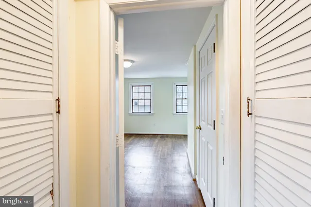 a view of a hallway with wooden floor and a bathroom