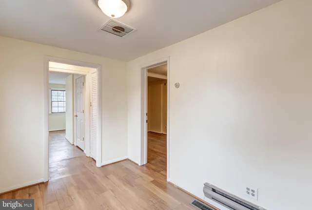 an empty room with wooden floor and a ceiling fan