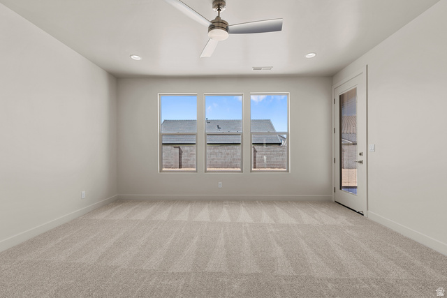 2955 East Rimrunner Drive St. George, UT 84790 - Photo 13 of 35 Spacious room featuring neutral carpeting, three large windows, a glass-paneled exterior door, a ceiling fan, and recessed lighting