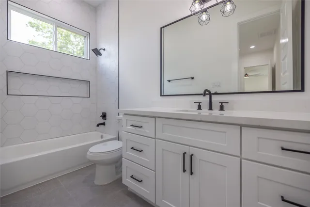 a bathroom with a toilet a sink a mirror a bathtub and vanity