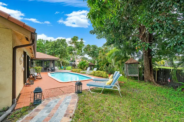 an outdoor sitting area with a table and chairs under an umbrella