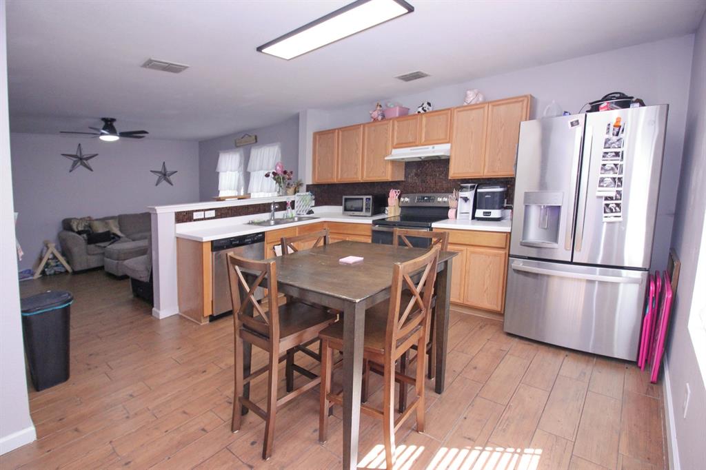 12609 Carpenter Lane Rhome, TX 76078 - Photo 18 of 29 Kitchen featuring wood-finish flooring, wood cabinetry, stainless steel appliances, and a breakfast bar with white countertops