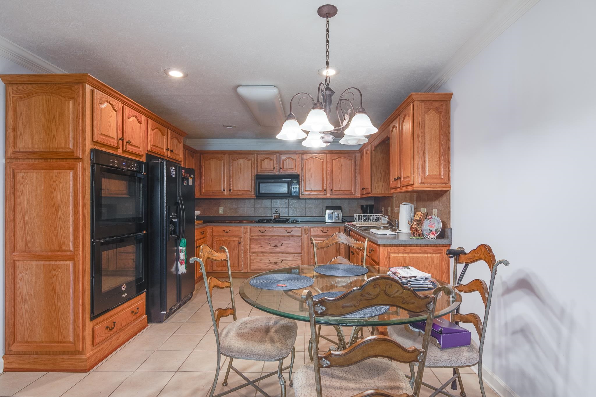 9102 Highway 76 Stanton, TN 38069 - Photo 12 of 27 Kitchen with crown molding, a chandelier, decorative backsplash, black appliances, and light tile patterned floors