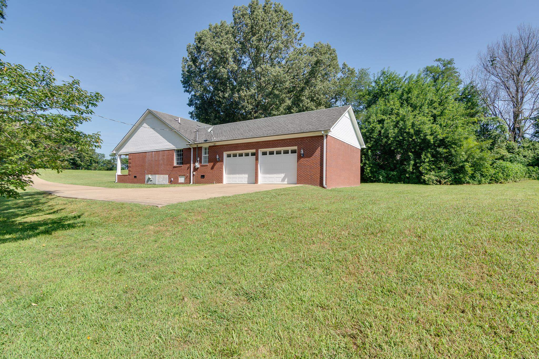 9102 Highway 76 Stanton, TN 38069 - Photo 24 of 27 View of property exterior with a garage, a lawn, driveway, brick siding, and roof with shingles
