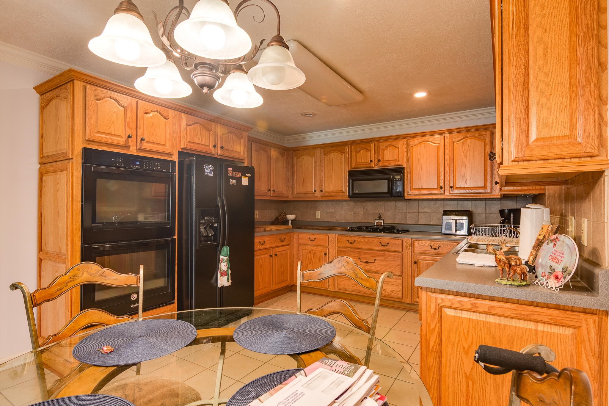 9102 Highway 76 Stanton, TN 38069 - Photo 9 of 27 Kitchen featuring black appliances, a chandelier, crown molding, light tile patterned flooring, and backsplash