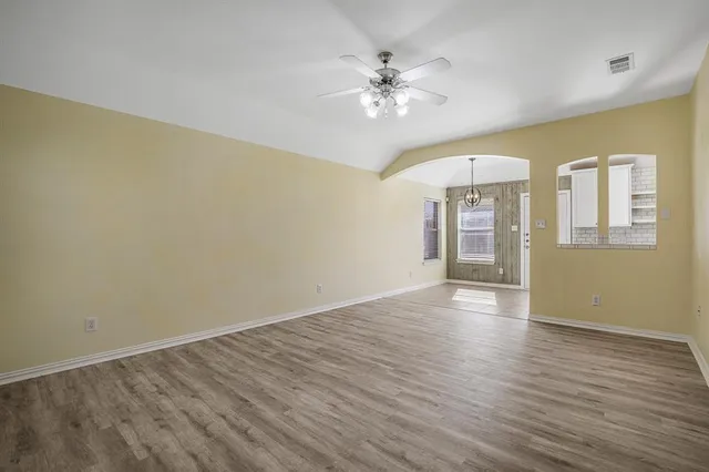 a view of an empty room with wooden floor and a chandelier