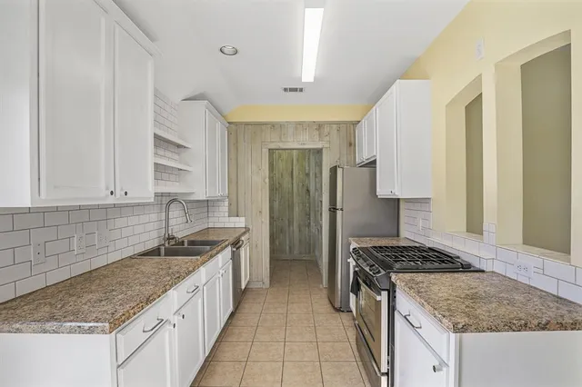 a kitchen with granite countertop a sink stove and refrigerator