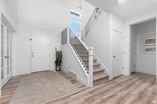 500 North 516th Street West, Unit 19 Mapleton, UT 84664 - Photo 12 of 41 Foyer featuring wood-finish flooring, a white paneled entry door, and a staircase with carpeted treads and black metal balusters