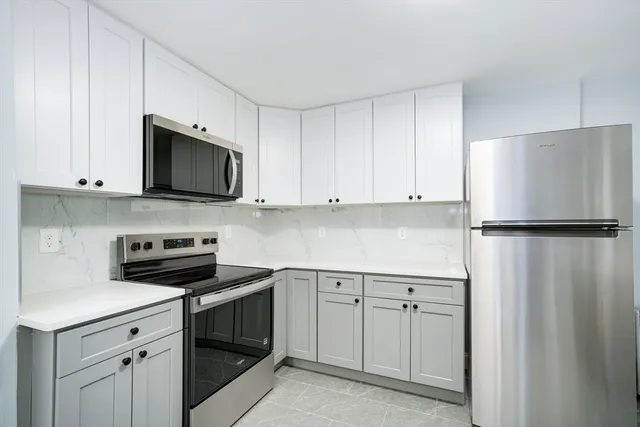 a kitchen with white cabinets and stainless steel appliances
