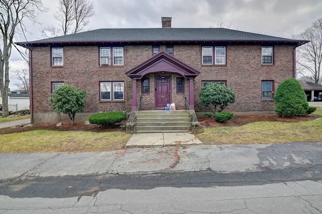 a front view of a house with a yard and potted plants