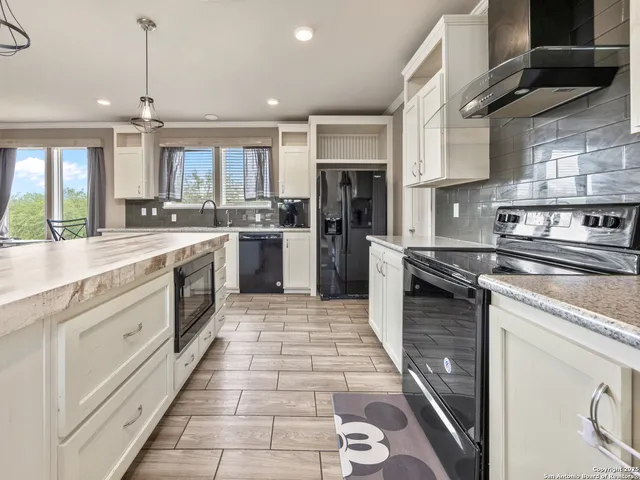 a large kitchen with stainless steel appliances granite countertop a stove sink and cabinets